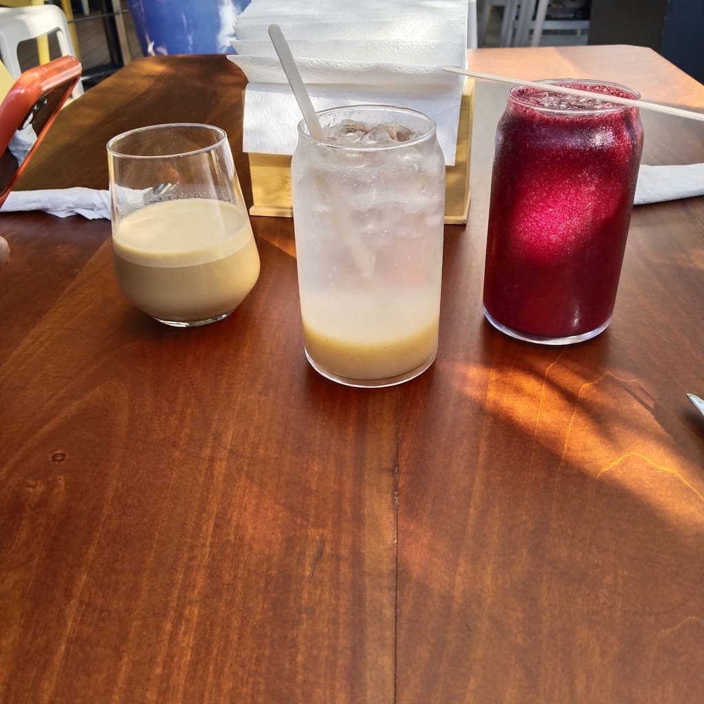 Tres bebidas de la casa sobre mesa de madera al sol