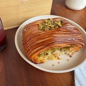 Croissant glaseado con pistache troceado en un plato de Pan y Miel.