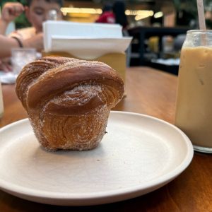 Cruffin azucarado de Pan y Miel servido con café helado.
