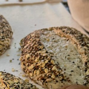 Hogaza de masa madre cubierta de avena y semillas recién formada en Pan y Miel.